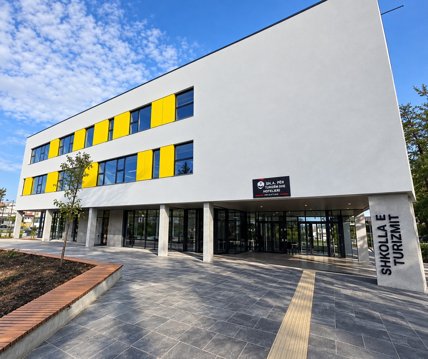 SHMLP "7 Shtatori" school building in Prishtina, yellow-shuttered facade and covered entrance