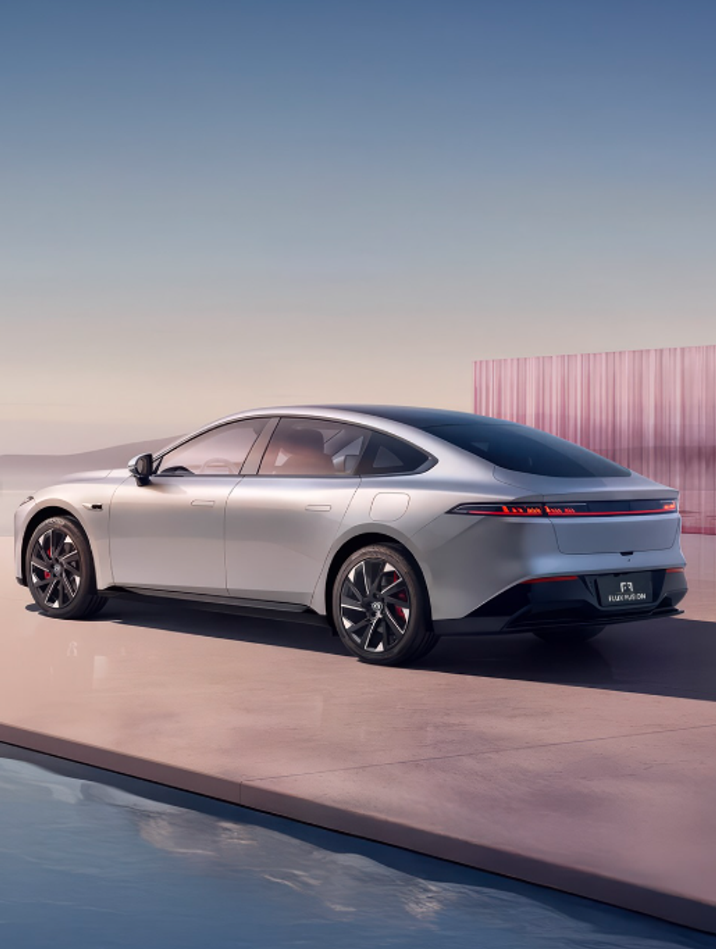 A silver electric sedan parked beside a reflecting pool at dusk