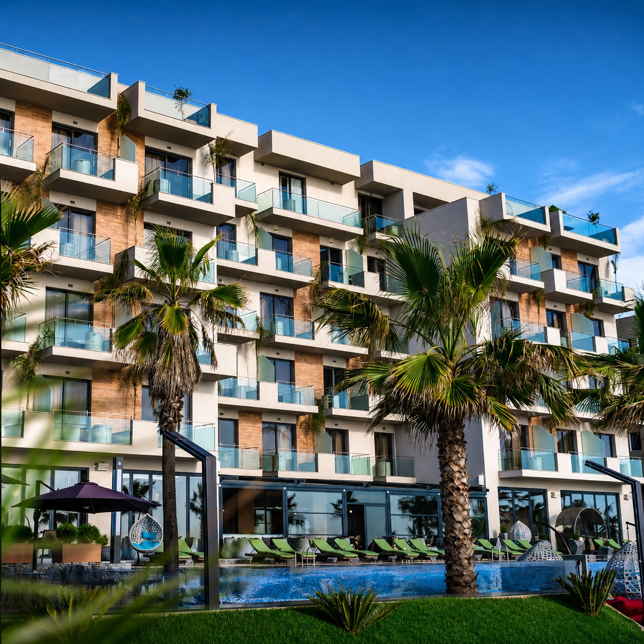 Hotel Pinea's beachfront facade at Golem, palm trees along the pool terrace