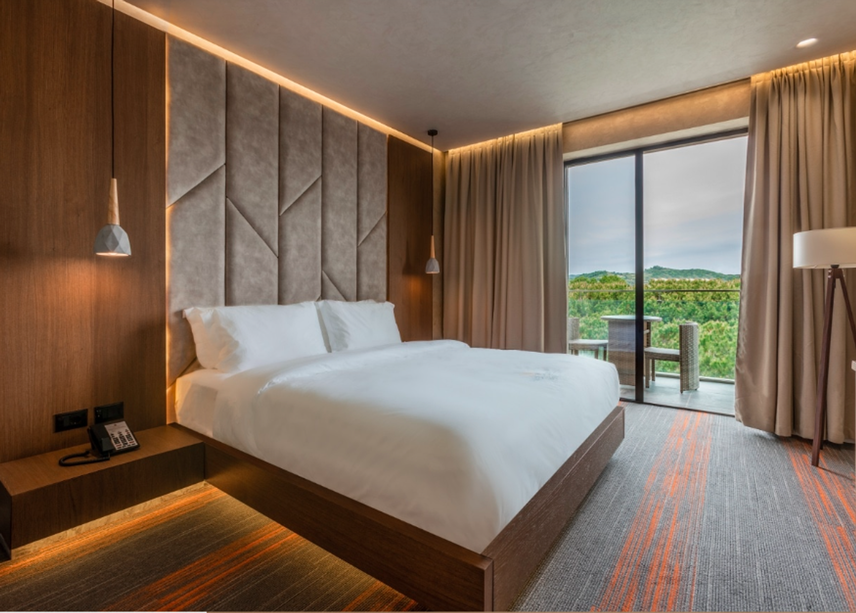 A Hotel Pinea Deluxe room, upholstered headboard and a private balcony over the treeline
