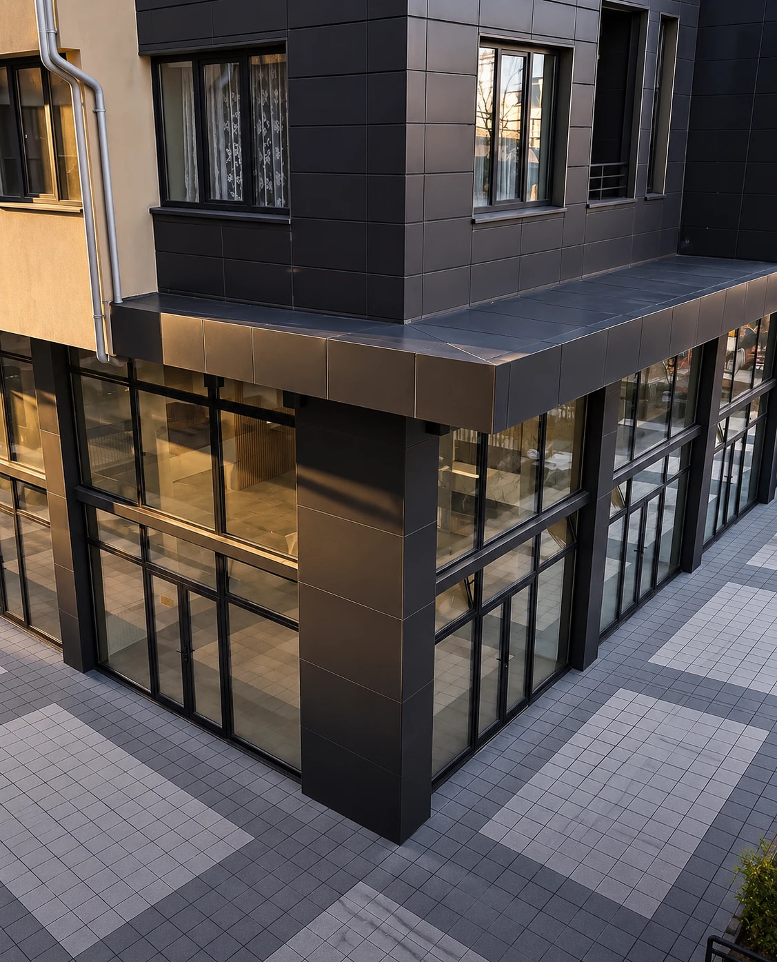 The ground-floor retail units at Kompleksi Donika 2, glass storefronts at golden hour