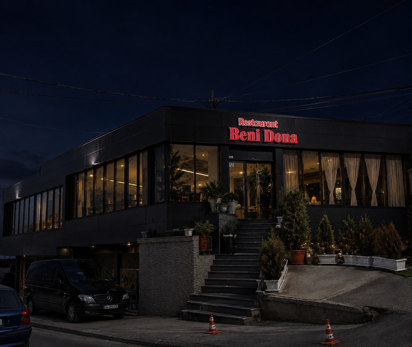 Restaurant Beni Dona at night, its lit sign and glowing dining room over the entrance steps